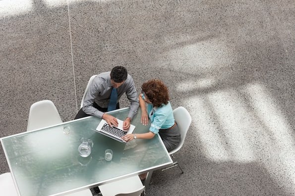 two people sitting at a table outside using a computer to build a staging site
